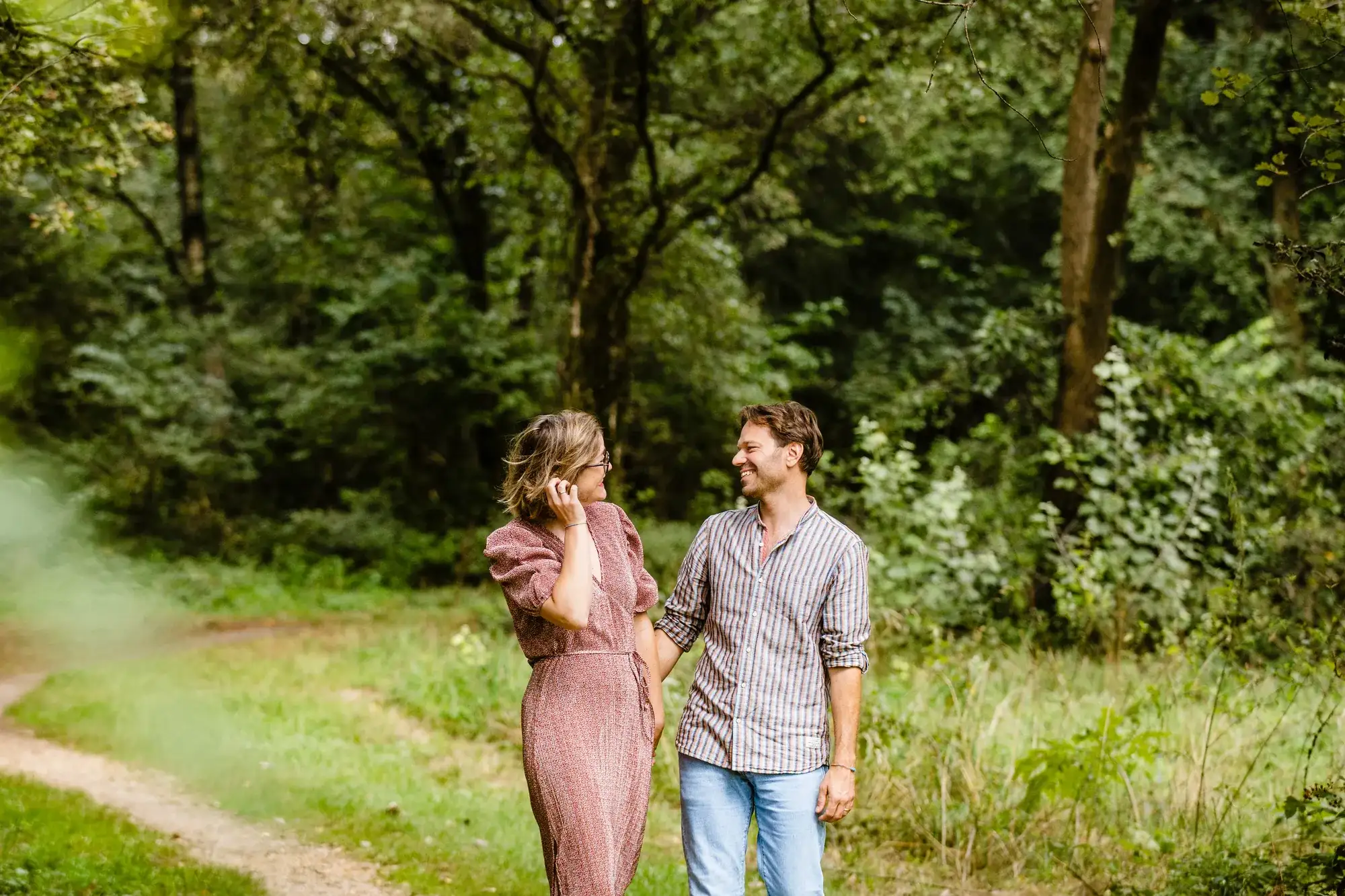 Couple laughing and looking at each other in a forest path