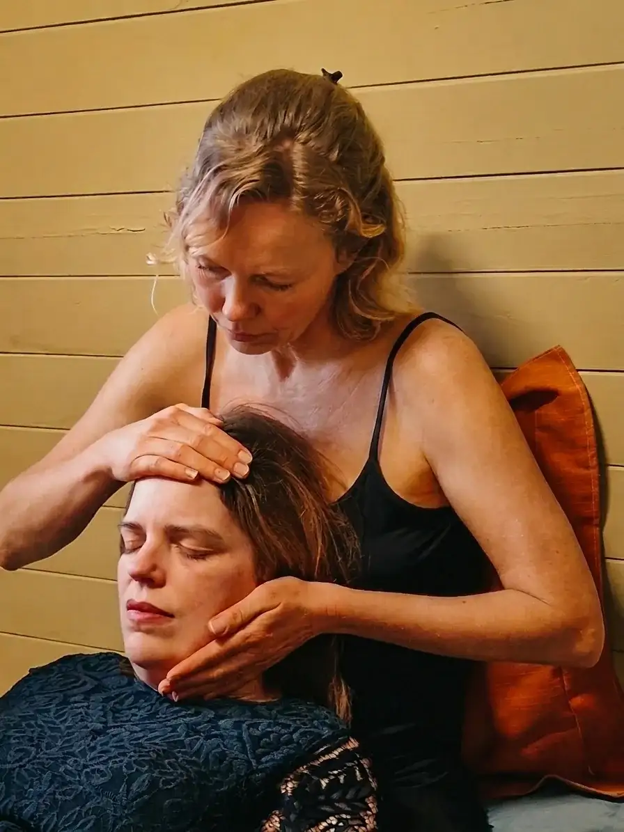 Chantal gently holding a client's face during a session, both present and at peace
