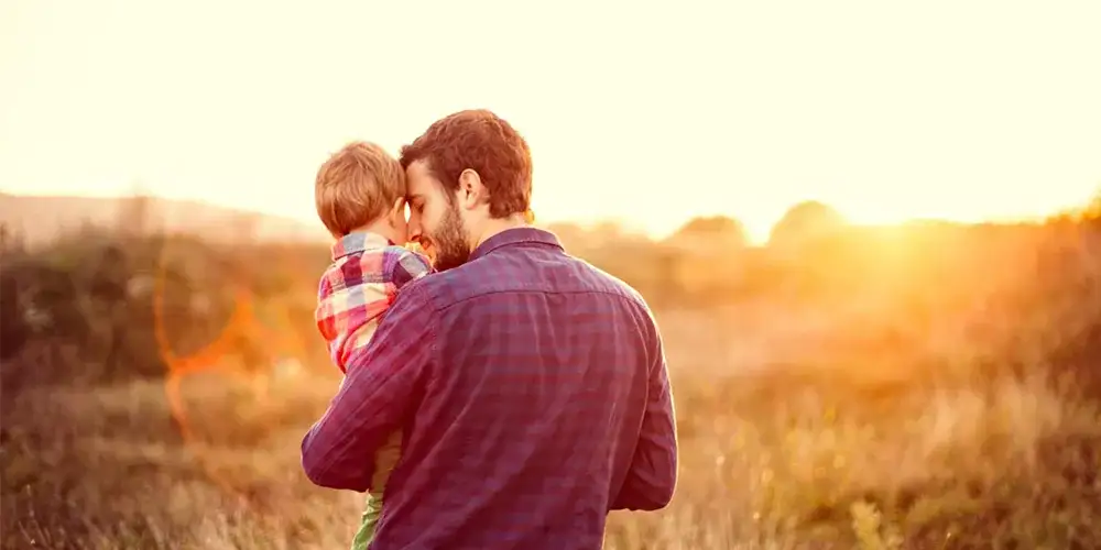 Father tenderly holding his child in a golden sunset field